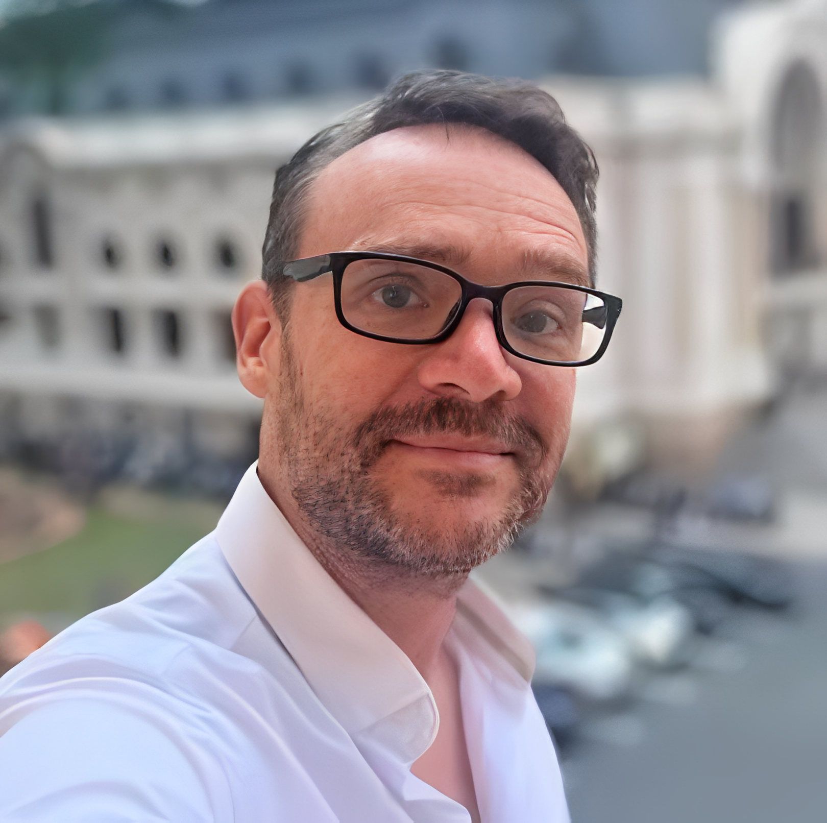 Bearded man with glasses taking city selfie