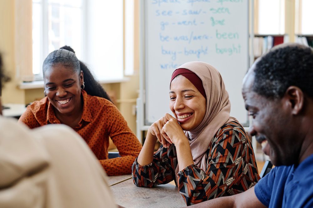 Adults smiling and chatting around classroom table